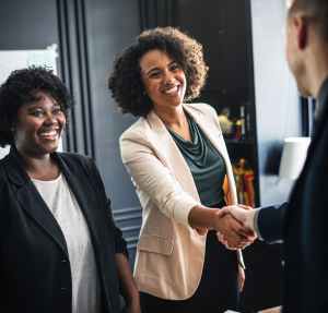 woman wears beige suit hand shaking man wear suit